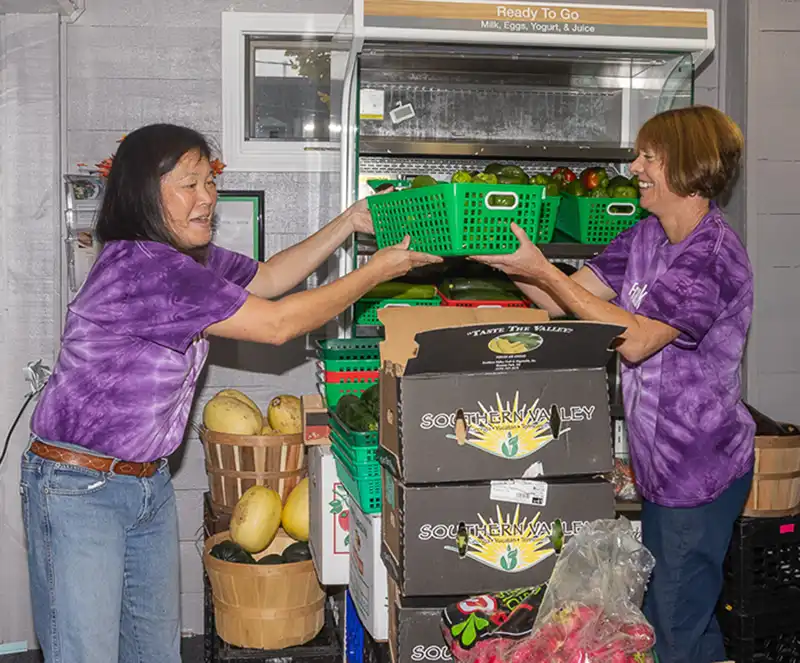 Food Pantry volunteers handing basket of fruit