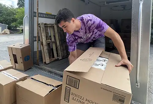 Male youth loading Pantry truck with boxes